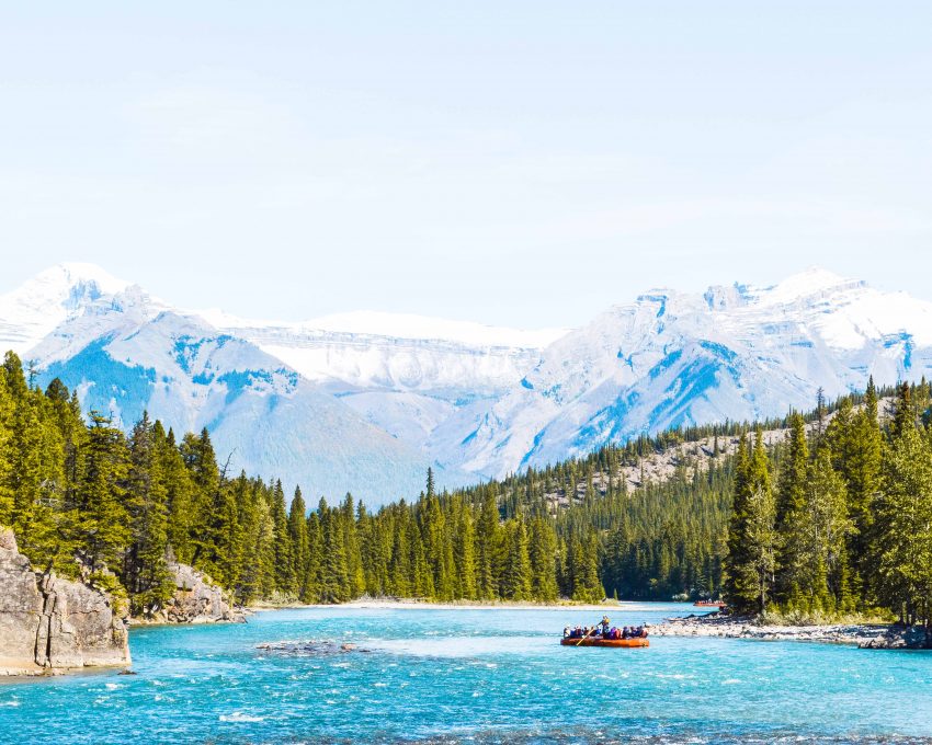 Snowy mountains, pine trees and a bright blue river in Banff in the Canadian Rockies.