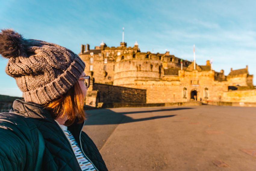 Side profile photo of myself looking towards Edinburgh Castle, glowing in the sunrise light.