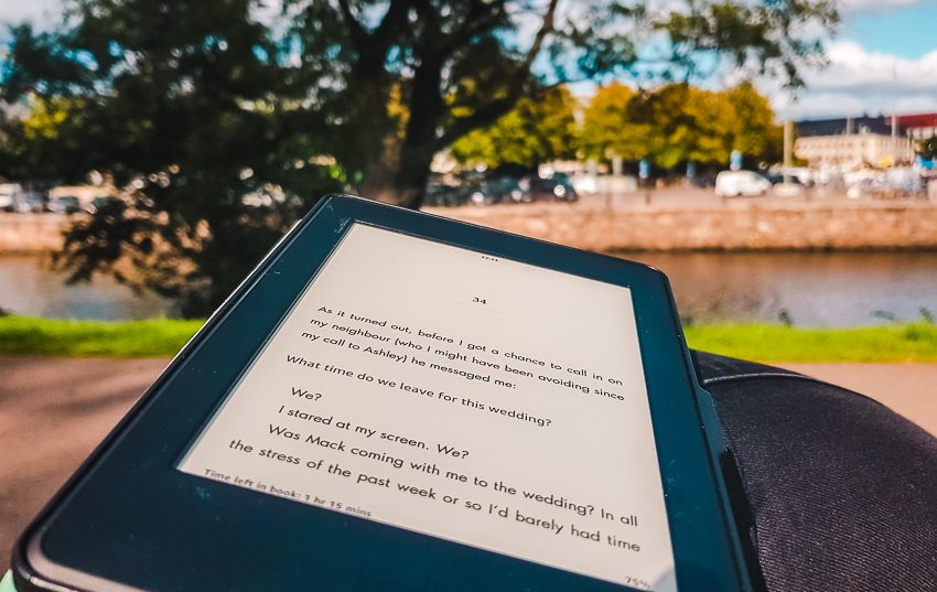 Reading my Kindle on a bench beside the river in Gothenburg, Sweden