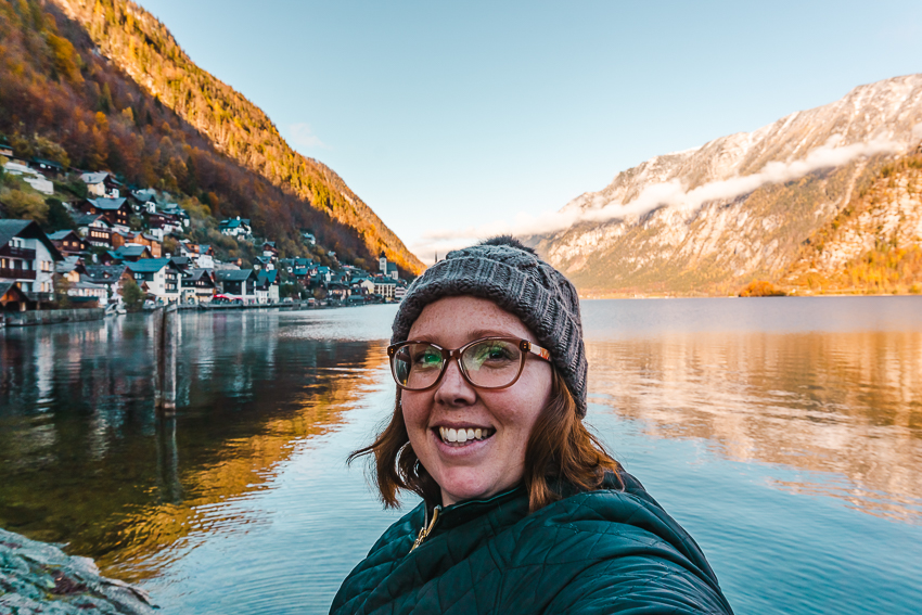 Me standing in front of a lakeside view in Hallstatt, Austria - one of the best day trips from Salzburg.