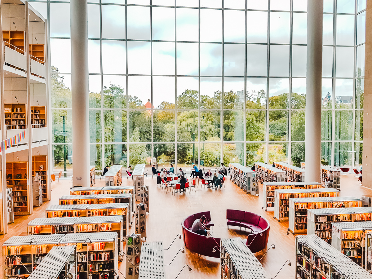 Things to do in Malmo, Sweden - visit the City Library, with a multi-story glass window looking out to a park.